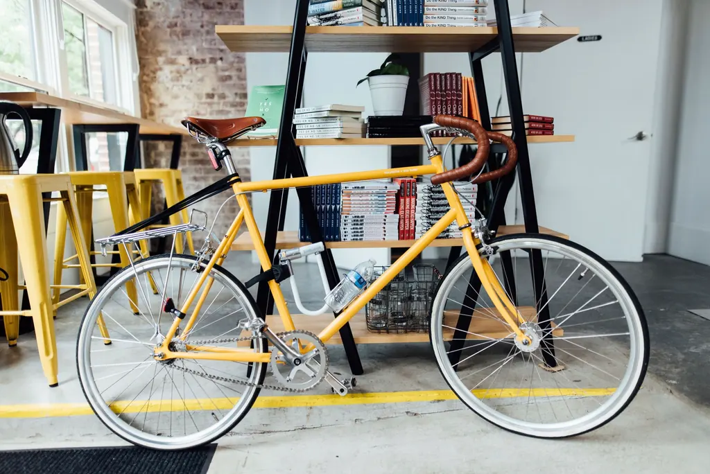 Bicicleta amarilla apoyada en una tienda luminosa con estanterías de madera
