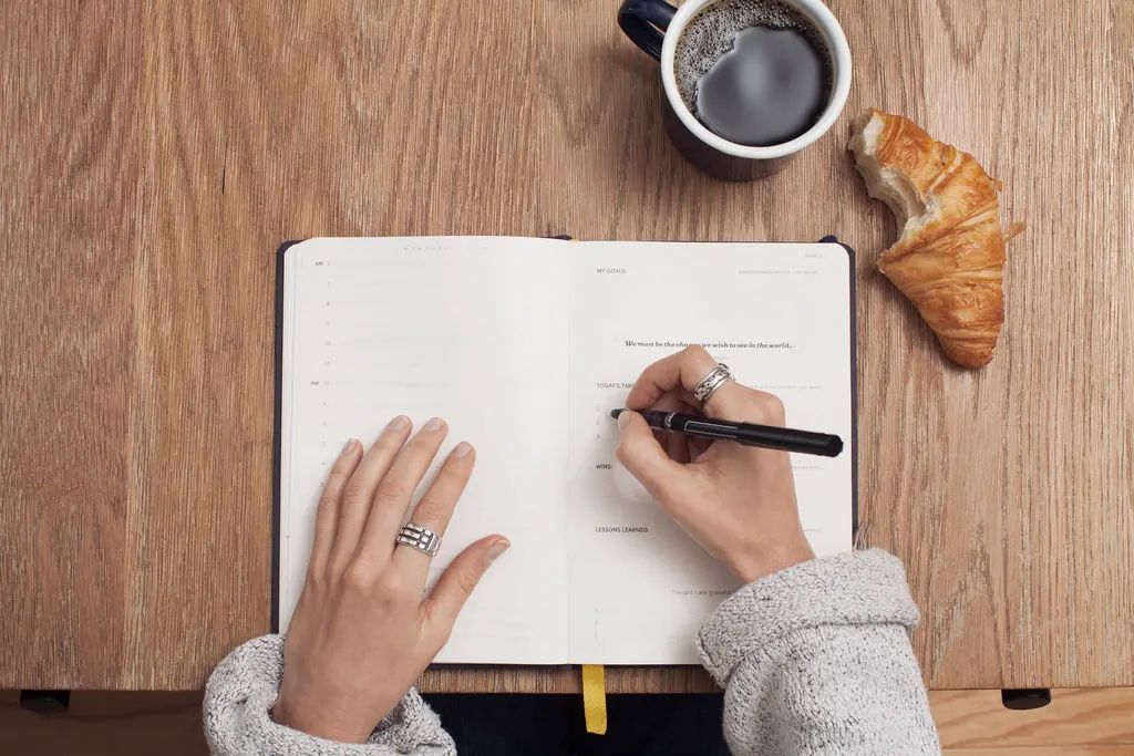 Escribiendo objetivos en un cuaderno junto al café